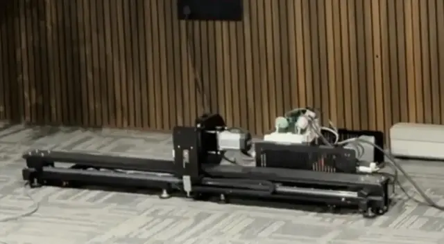 A motorised rail unit on the floor, wired to a control box